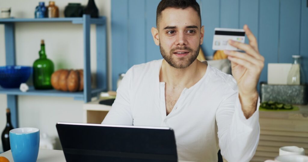 Man bekijkt webshop op laptop met creditcard